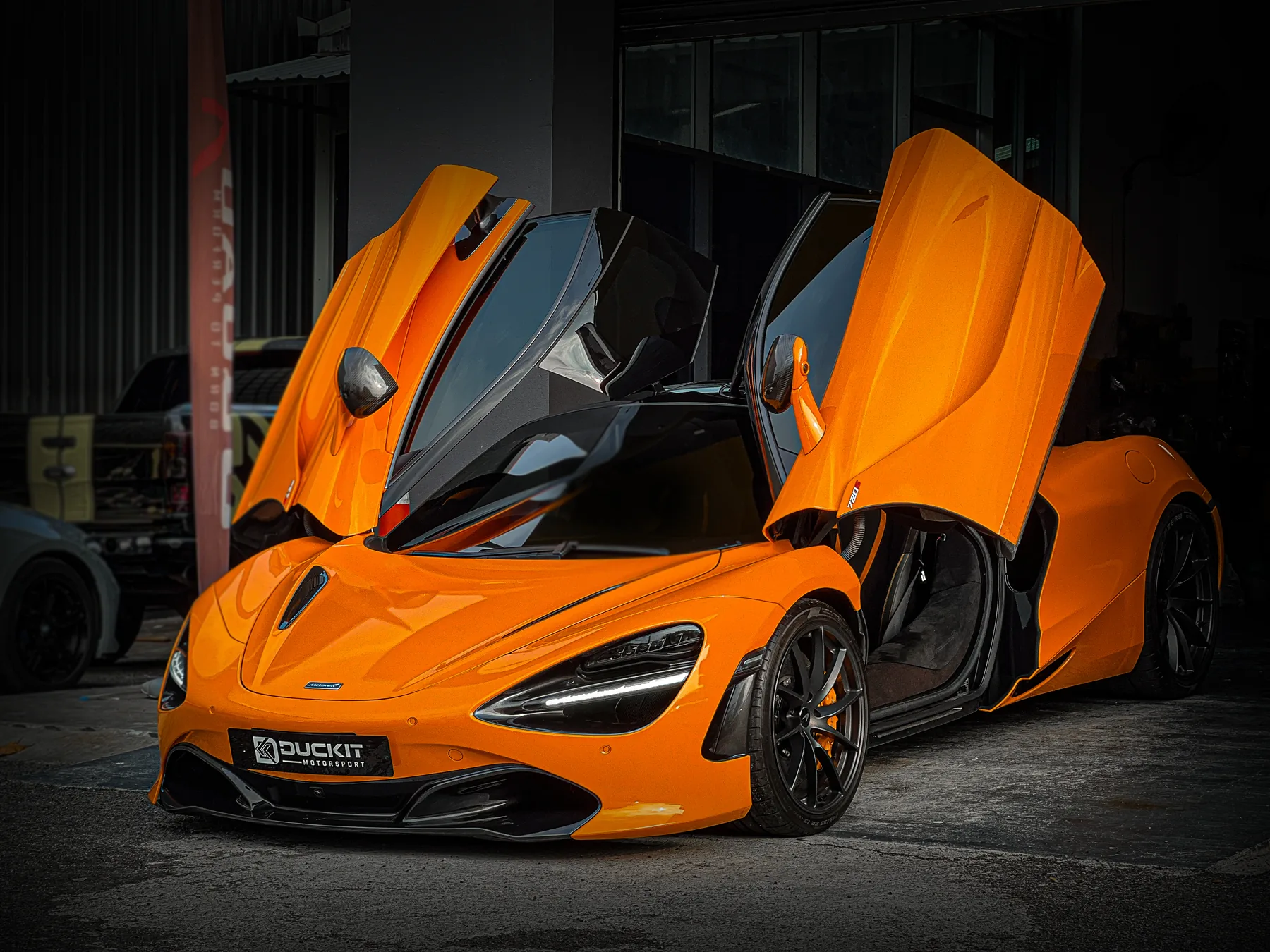 Orange McLaren with dihedral doors raised inside the Duckit workshop